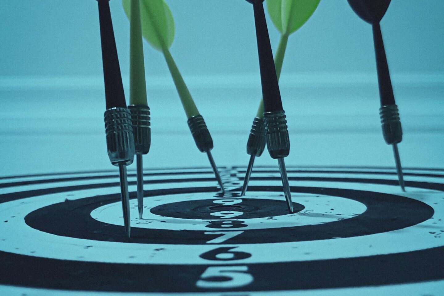 Close-up view of darts hitting a bullseye on a target board, symbolizing precision and focus.